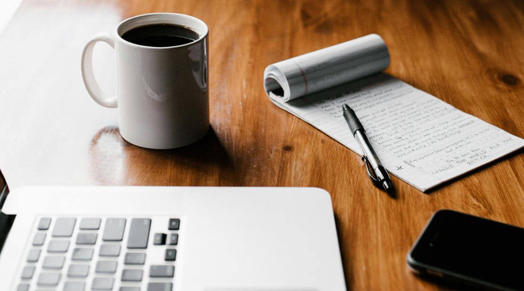 Laptop, notepad and coffee cup on a table