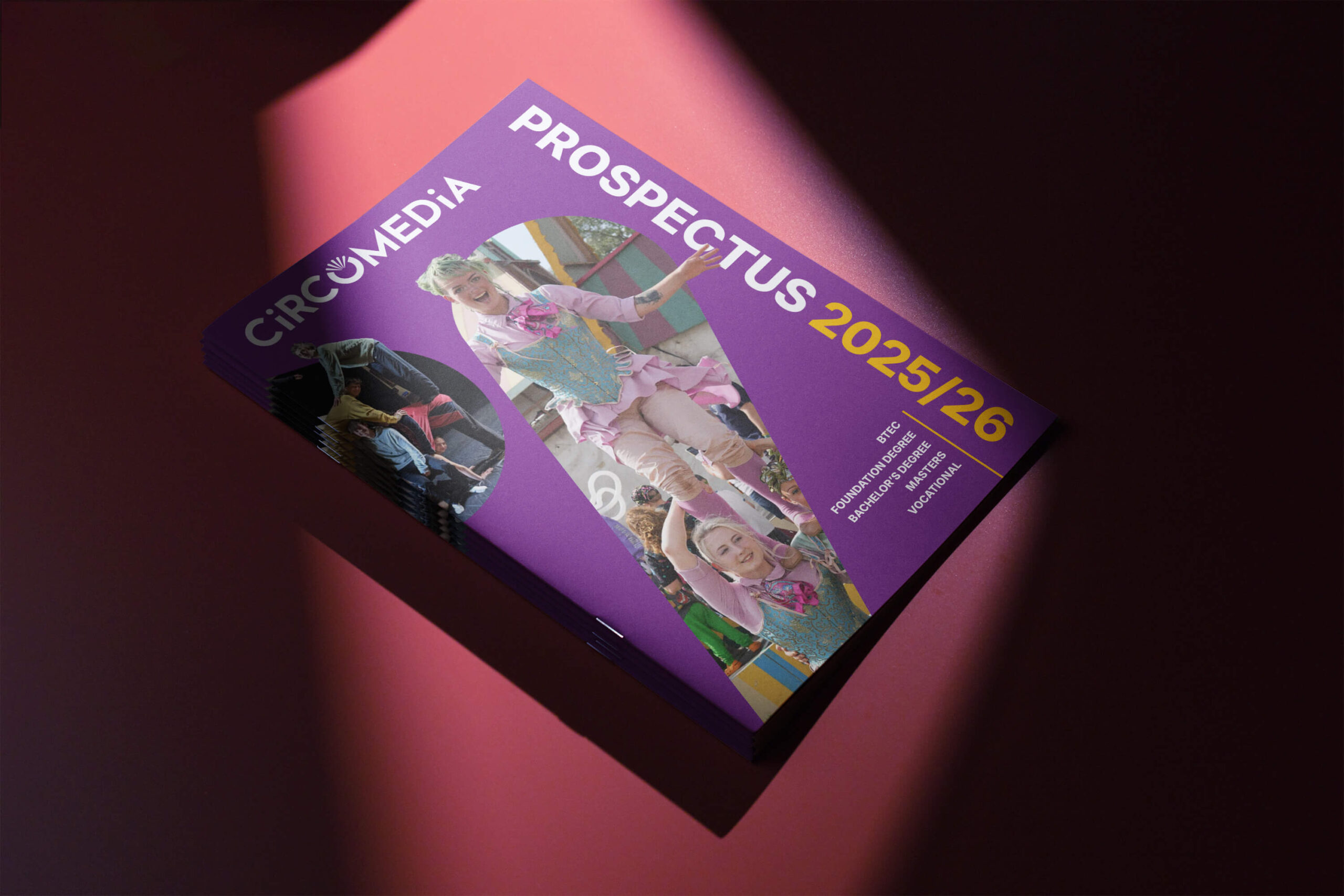 Circomedia's prospectus 2025/26 on a red background with a spotlight shining down on to it.