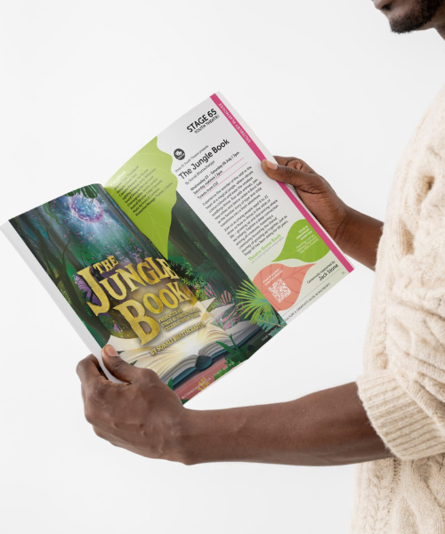 Jungle Book season brochure 2 500x600px A man wearing a woolie patterned jumper holding Wiltshire creative's show brochure. The page is opened to show the Jungle book with a big image on one page and the marketing text on the other.
